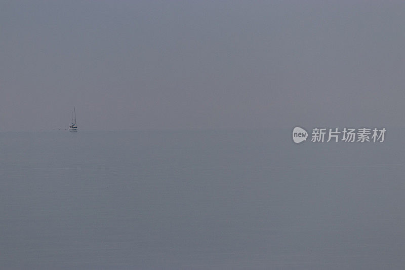 一艘帆船迷失在空旷的雾茫茫的海面上