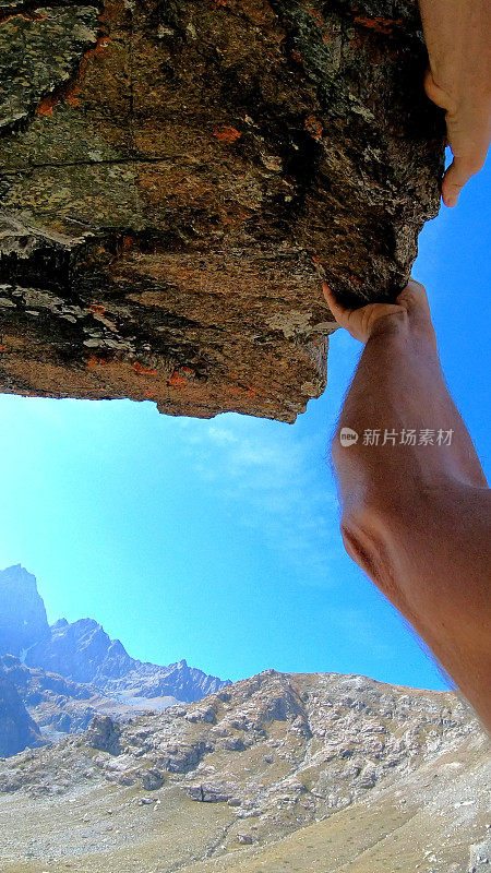 日出时，男性攀登者登上岩石顶峰