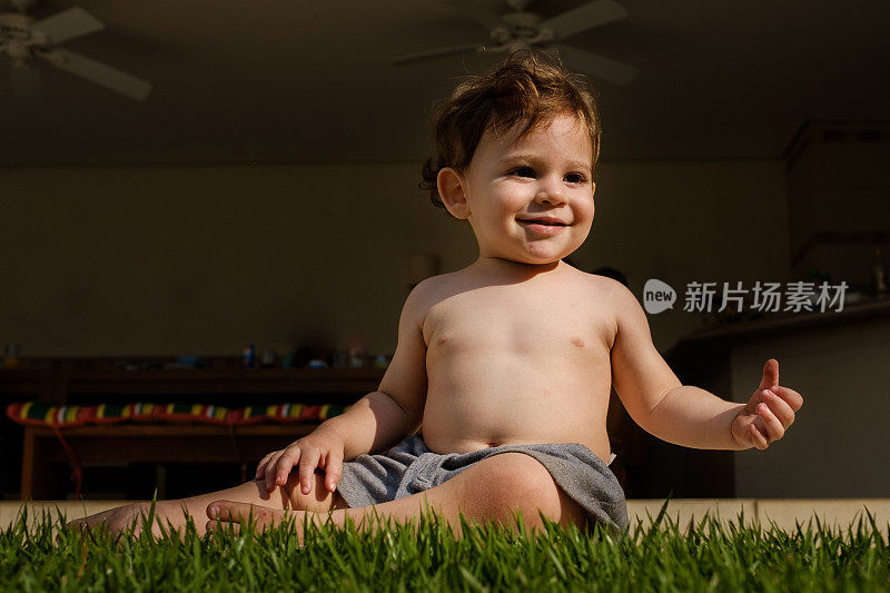 小男孩微笑着坐在草地上