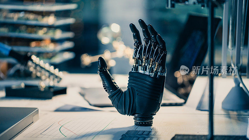 一个未来的假体机器人手臂的特写站在一个高科技研究实验室的桌子上，有现代计算机设备。