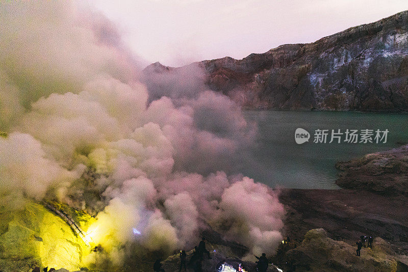 印度尼西亚东爪哇，伊真火山的壮观日出，蓝色的火焰和明亮的黄色硫磺蒸汽在绿松石湖之上