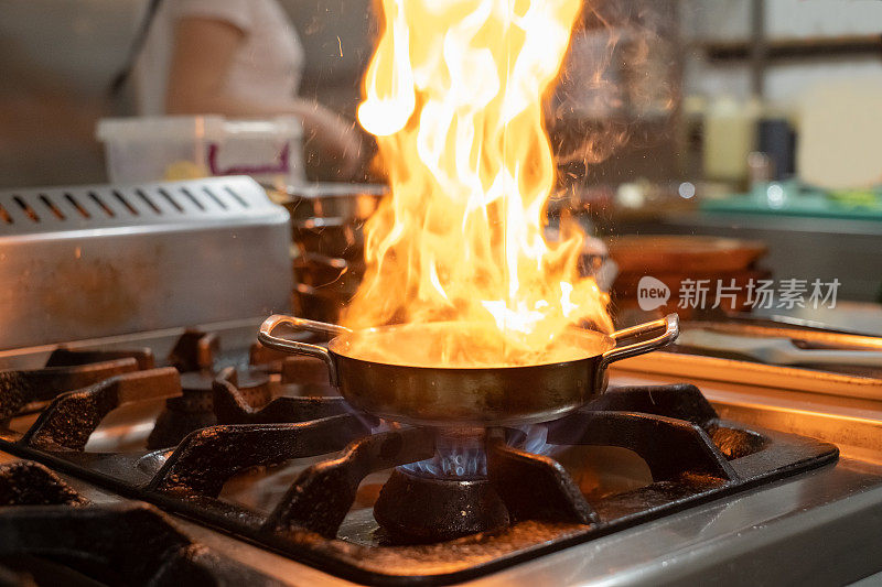 在厨房炉子上用煎锅用火焰烹饪