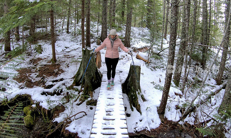 女性徒步旅行者走过被雪覆盖的木板路