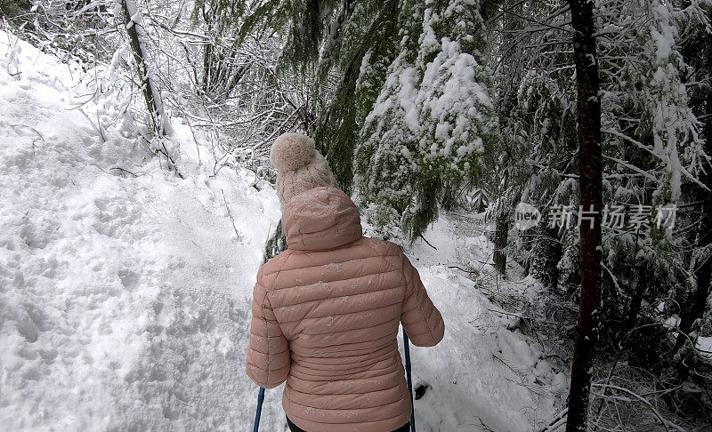 女性徒步旅行者沿着雪道行走