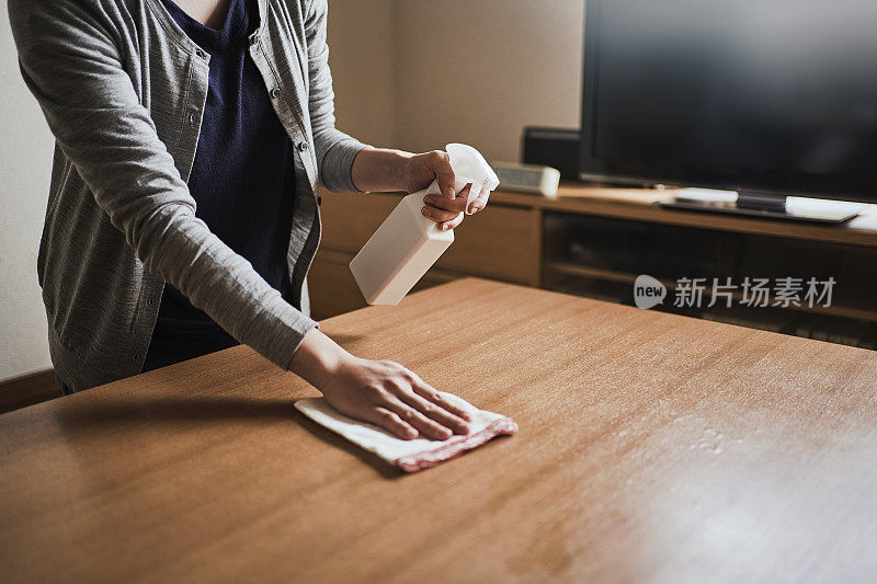 女人用酒精消毒家里的桌子