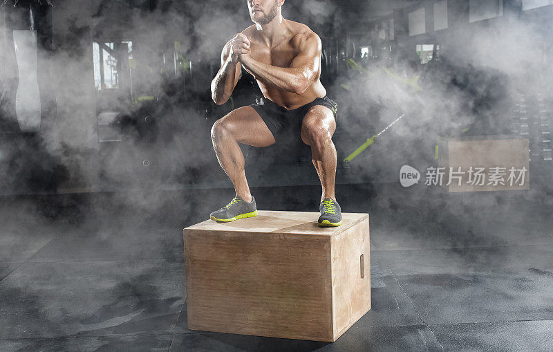 健美男，做有氧运动，在健身房的木箱上跳。运动概念，脂肪燃烧和健康的生活方式。