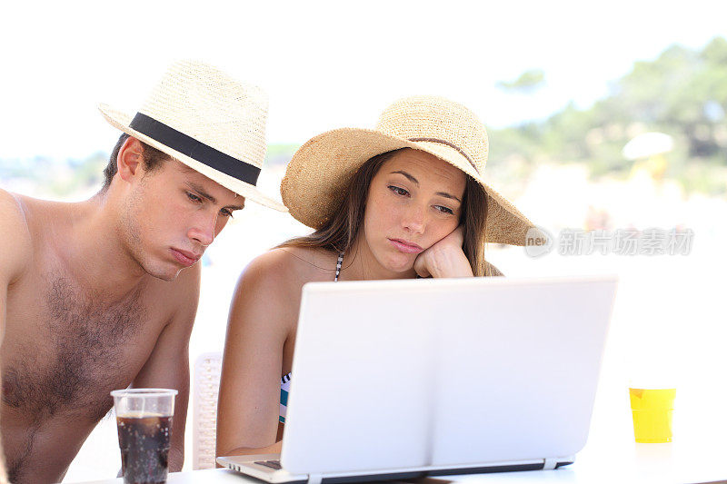 沮丧的游客在海滩上用笔记本电脑接收坏消息