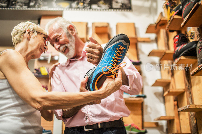 一对老年情侣在户外器材店一起挑选攀岩靴