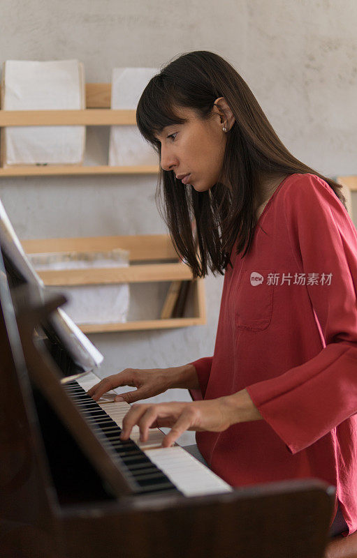 美丽的年轻女子在家里弹钢琴