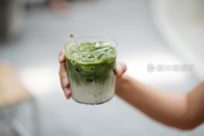 年轻女子手捧一杯日本抹茶拿铁冰