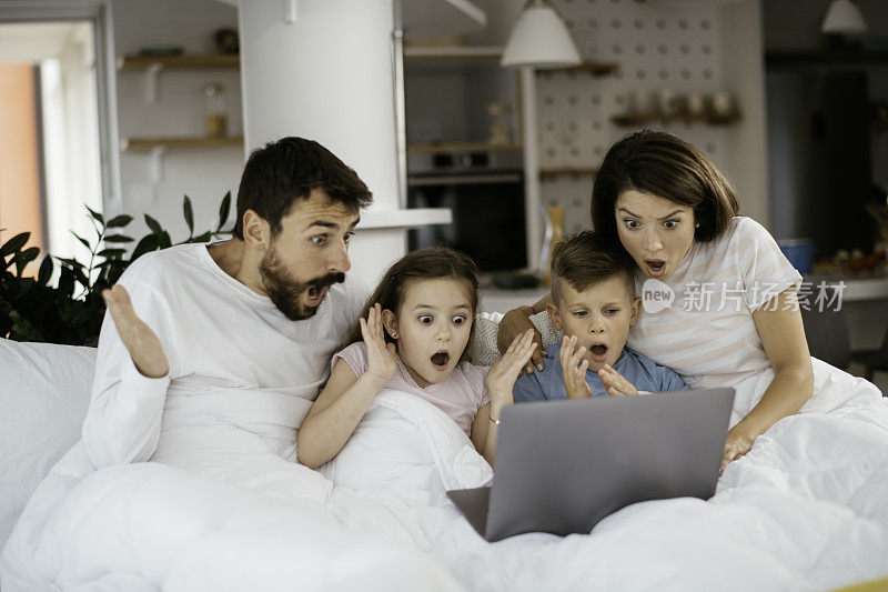 一家人躺在笔记本电脑上看电影的照片