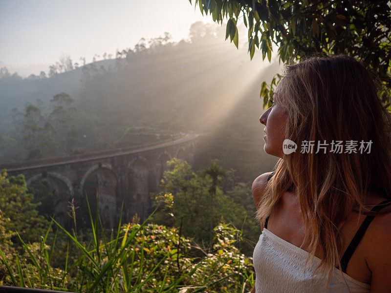 女游客在日落时凝视着著名的大桥