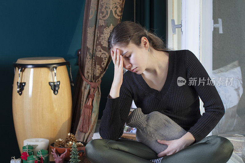 一个年轻女子在月经期间胃痛，她正在用一个热水袋敷在她的胃上