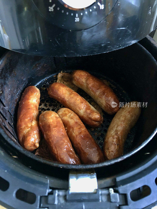 金棕色的形象，香肠在空气炸锅煮，比煎锅煮更健康，高视角