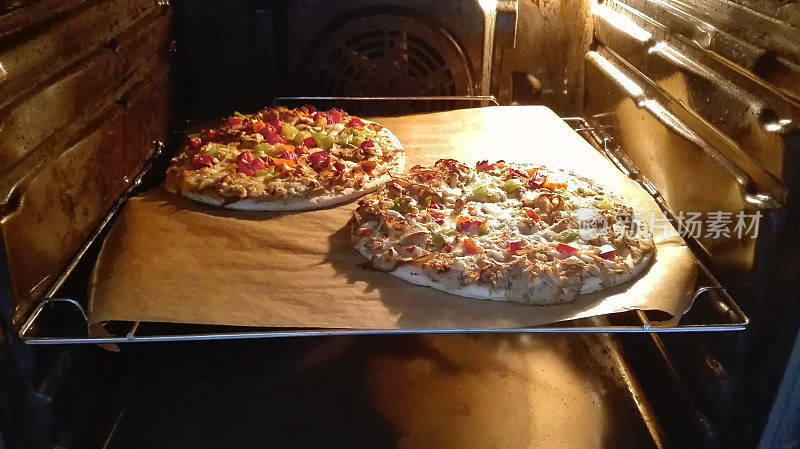 自制披萨在热烤箱烘烤的图像，在防油的羊皮纸上煮熟的薄而脆的基础
