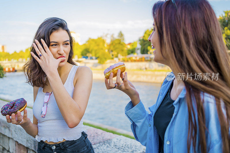 两个年轻女人在吃甜甜圈