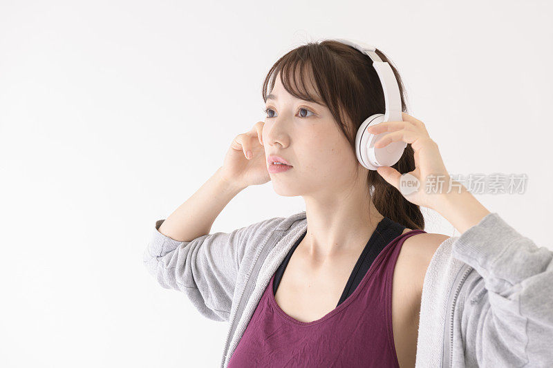 一名年轻女子戴着耳机，在工作室的白色背景前斜视着。