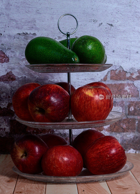 三层圆形玻璃果盘，上面有红苹果