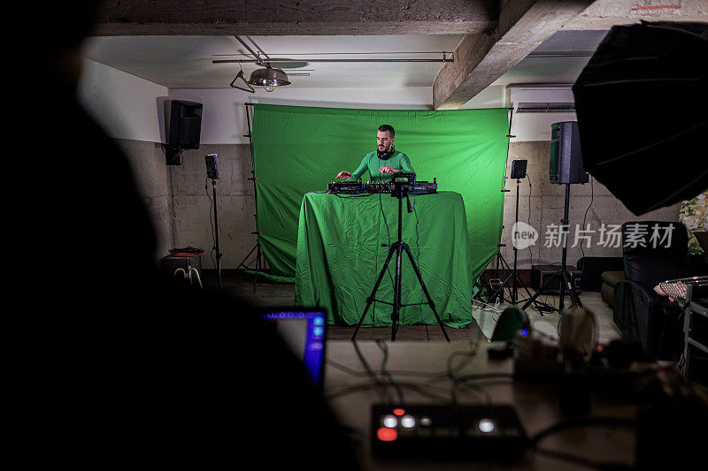 在电影摄影棚，DJ在绿幕前录制音乐