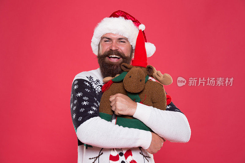 我所需要的就是假期。快乐圣诞老人抱玩具礼物粉红色背景。大胡子男人的笑容带着节日的气息。圣诞和新年晚会。节日的庆祝活动。节日礼物交付