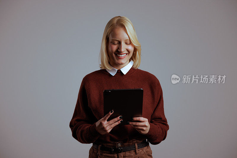 一个面带微笑的白人妇女，正在检查她的新平板电脑的规格。