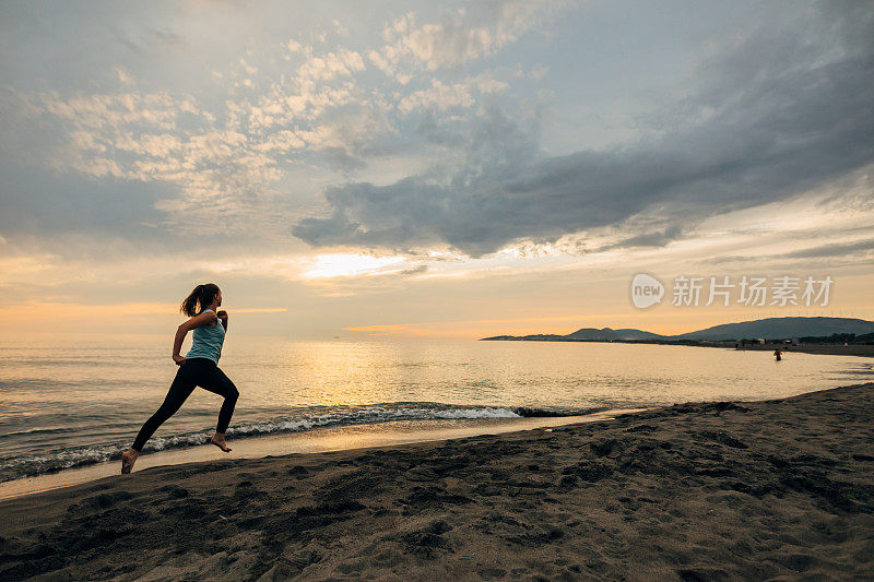 一名女子用手机拍摄海上美丽日落的背影。