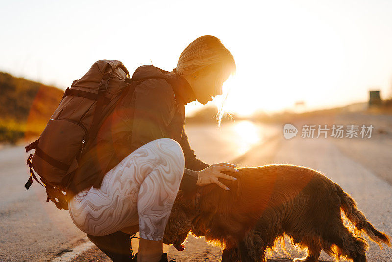日落时分，一名年轻女子和她的狗狗在外面亲热