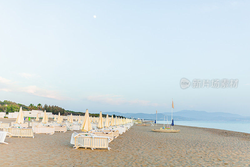 上午在海滩。在海边迎接黎明。夏天的背景。放松的地方。在海上休闲。伞椅海滩。美丽的早晨的风景。欧洲旅游