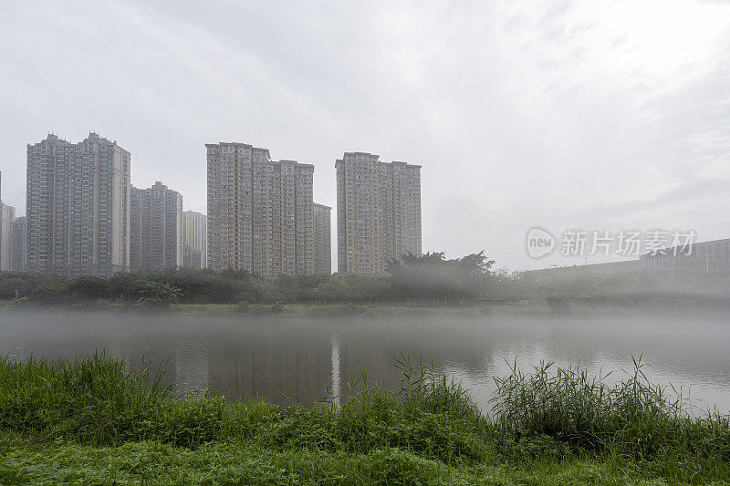 晨雾中的城市映衬着湖边的高楼大厦