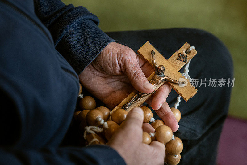 一个老人的手和耶稣的十字架。