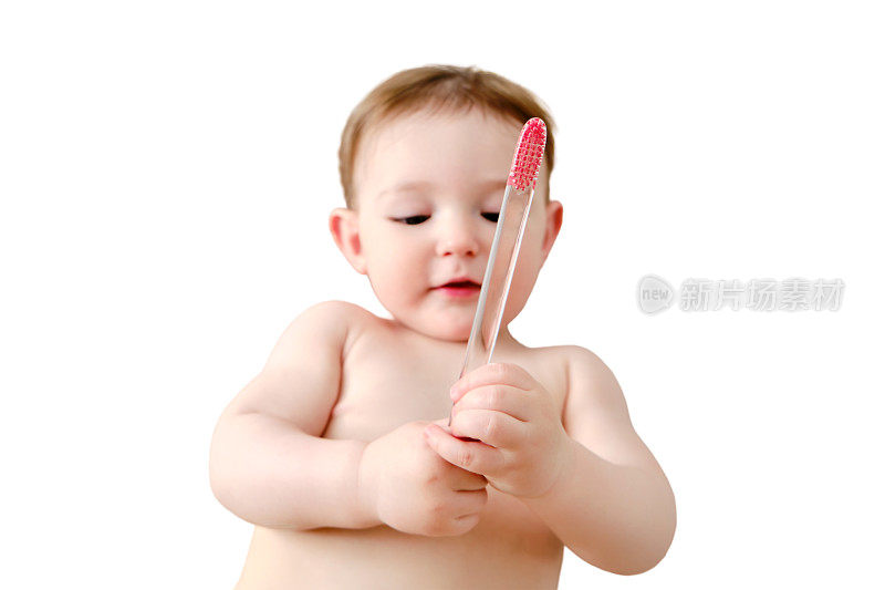 孩子在白色背景上用牙刷刷牙。快乐的学步婴儿躺在家里的床上学着刷牙。一岁儿童
