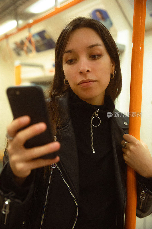 女子在地铁上使用智能手机