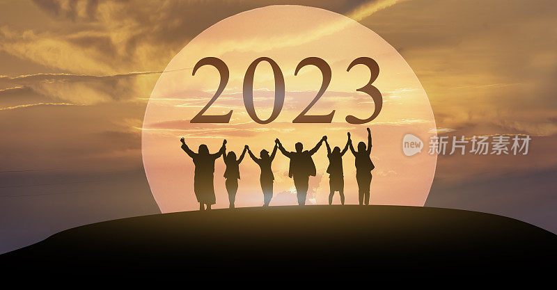 2023新年快乐，一起战斗，2023字母的剪影在山上与商务人士高举双臂在日出的团队合作理念。