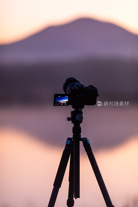 三脚架上无反光镜相机拍摄日出湖景
