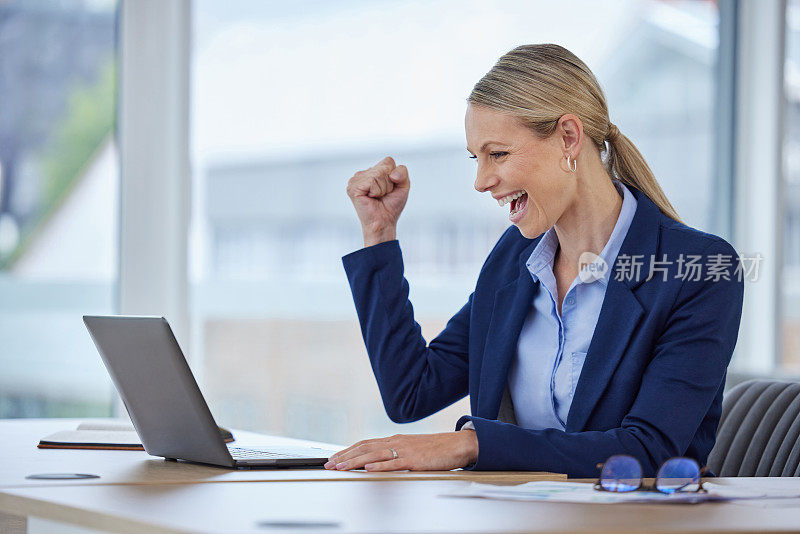 快乐的商业女性在笔记本电脑上庆祝工作的成功，阅读带有好消息的电子邮件，在工作中为办公室的胜利欢呼。微笑，专业和企业女老板在线交易