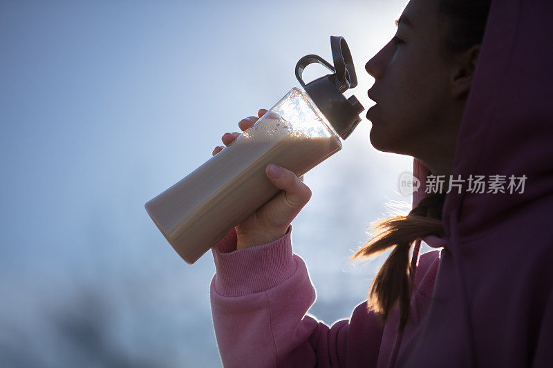 年轻女子在公园慢跑时补水。