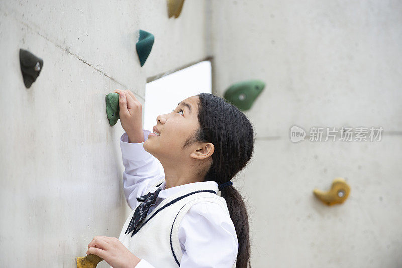 穿着校服的女学生在爬抱石墙