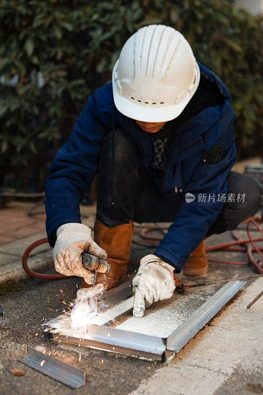 一名中年男性工人正在使用切割机和焊机