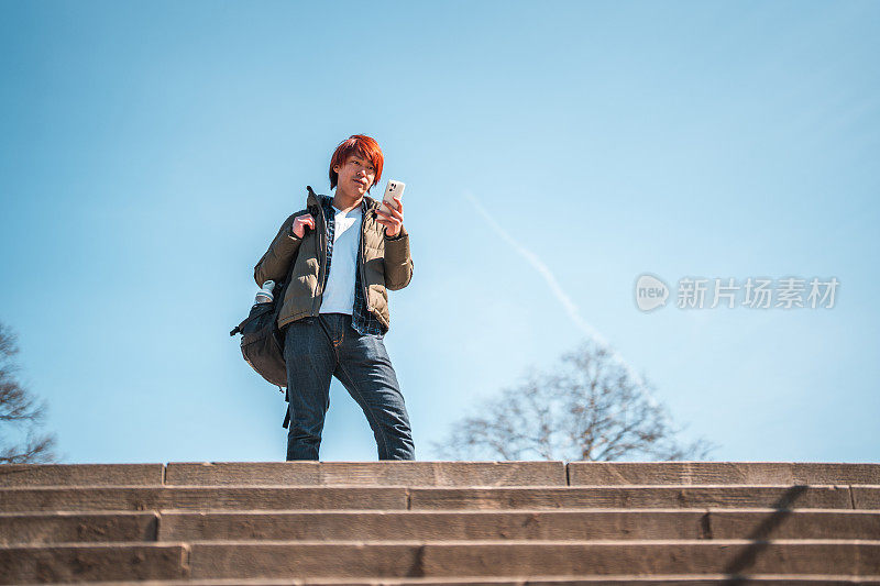 红发亚洲男性在台阶上用手机
