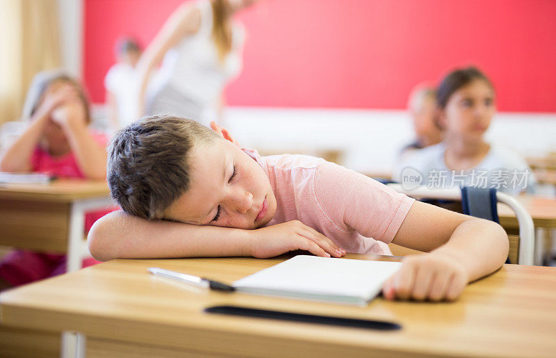 上课时，一个疲惫的学生在教室里睡觉