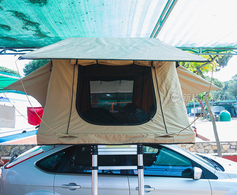 一张帐篷的照片，放在一辆多功能车的车顶上。