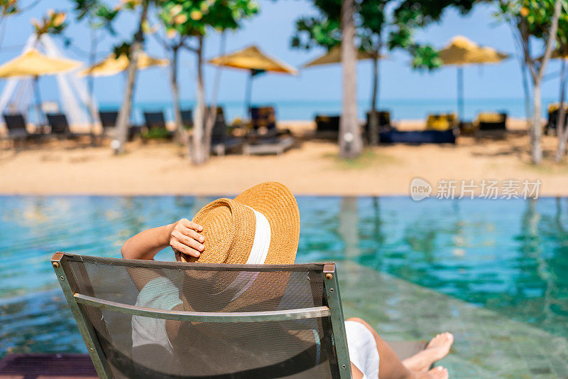 年轻的女性旅行者放松和享受海滩景色的热带度假泳池，而旅游暑假，旅游生活方式的概念