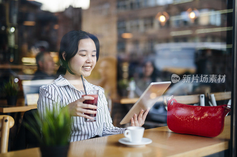 女子在咖啡厅用平板电脑上网银行。