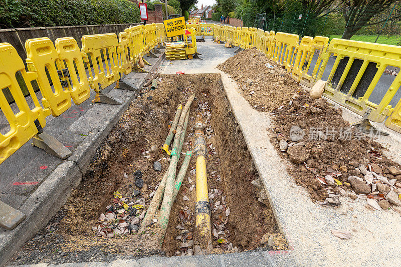 英国的道路工程正在挖掘当地的柏油路面，以修复地下的公用管道，并设置安全屏障和标志