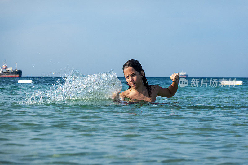 他用手在海里泼水。一个夏天的早晨。忒涅多斯岛。爱琴海北部，12岁的帅哥。长头发的