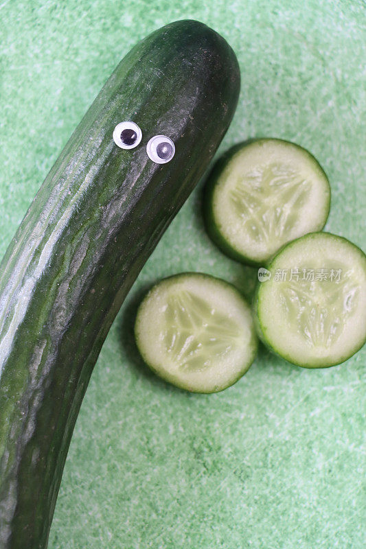 有趣的特写形象，卡通人物由长着大眼睛的黄瓜制成，蔬菜片在斑驳的绿色背景上，儿童健康饮食，幽默的概念
