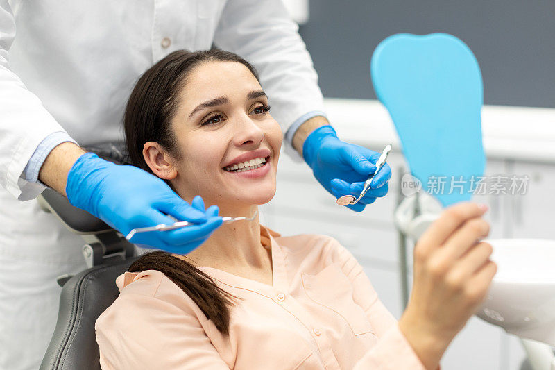 妇女在洗牙和牙科咨询后检查笑容。牙科和快乐的女病人与正畸医生进行口腔卫生，健康和清洁