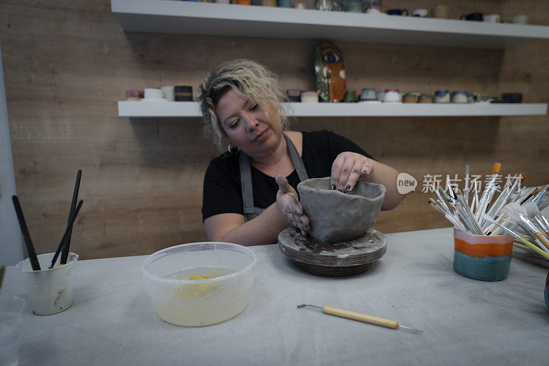女陶工在陶轮上用湿粘土制成的围裙状花瓶里
