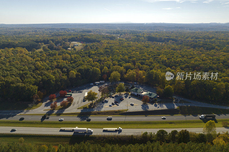 在繁忙的多车道美国高速公路附近的大型休息区的俯视图，快速移动的汽车和卡车。州际旅行期间的休闲休息场所