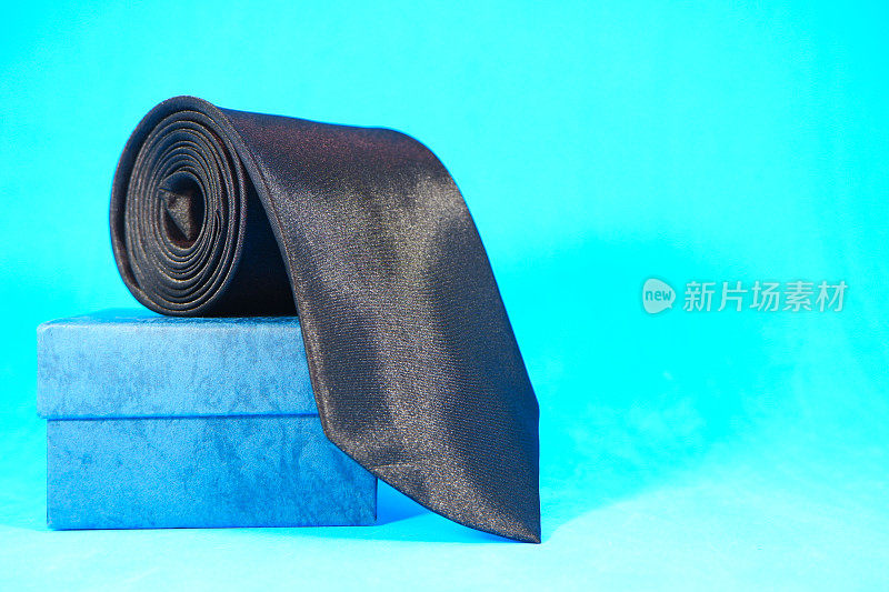 普通织物黑色领带卷在普通背景上的特写视图单一对象